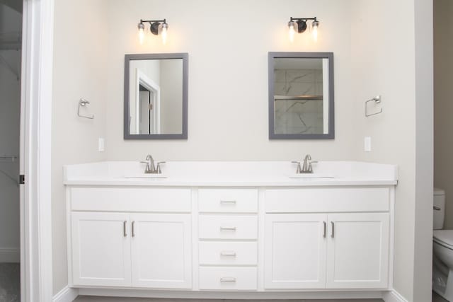 bathroom featuring toilet and dual vanity