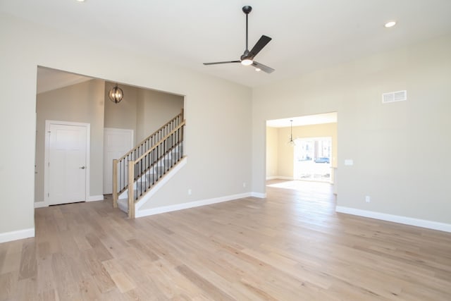 empty room featuring vaulted ceiling, light hardwood / wood-style floors, and ceiling fan with notable chandelier