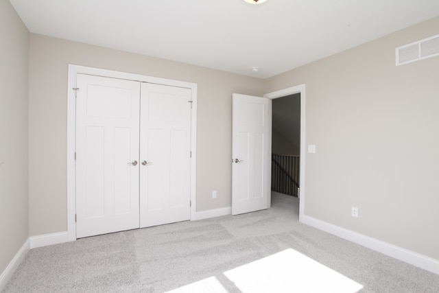 unfurnished bedroom with a closet and light colored carpet