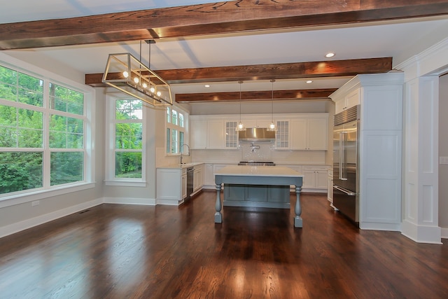 kitchen with stainless steel appliances, white cabinets, a kitchen island, and decorative light fixtures