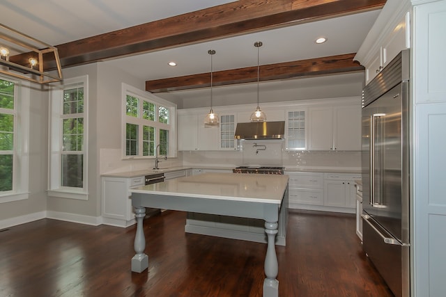 kitchen with a breakfast bar, stainless steel built in refrigerator, white cabinets, wall chimney exhaust hood, and hanging light fixtures