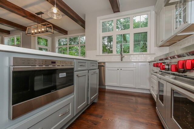 kitchen featuring hanging light fixtures, dark hardwood / wood-style flooring, tasteful backsplash, and beamed ceiling