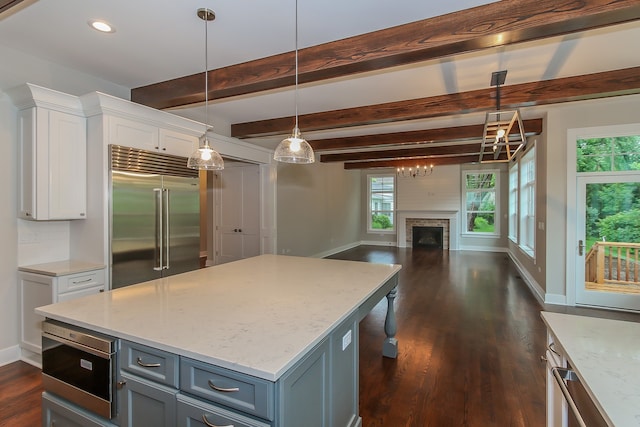 kitchen with dark hardwood / wood-style floors, built in refrigerator, light stone countertops, decorative light fixtures, and white cabinetry