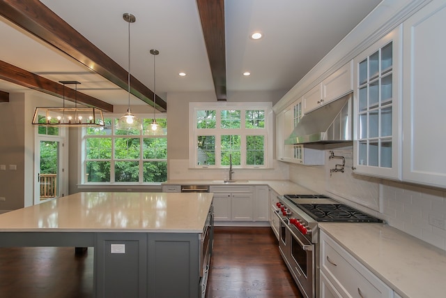 kitchen with white cabinetry, hanging light fixtures, sink, a center island, and range with two ovens