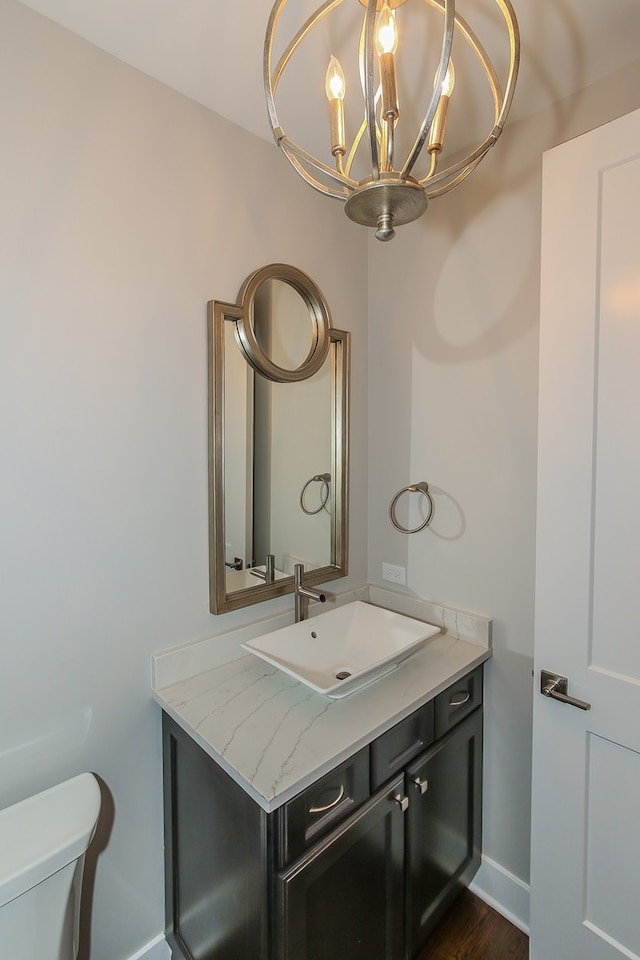 bathroom featuring a notable chandelier, toilet, oversized vanity, and wood-type flooring