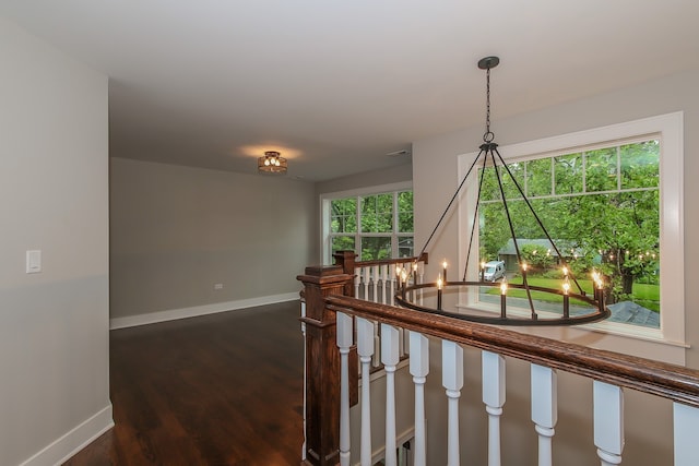 hall with a chandelier and dark wood-type flooring