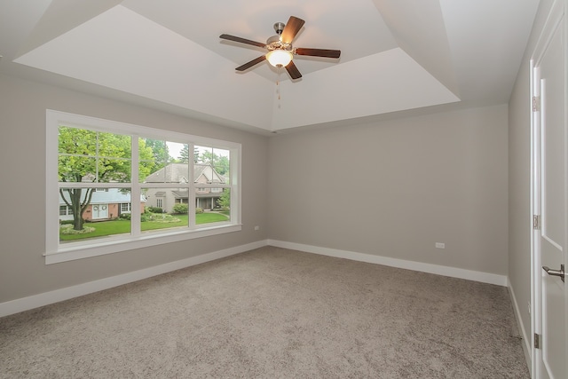 carpeted spare room featuring ceiling fan and a tray ceiling