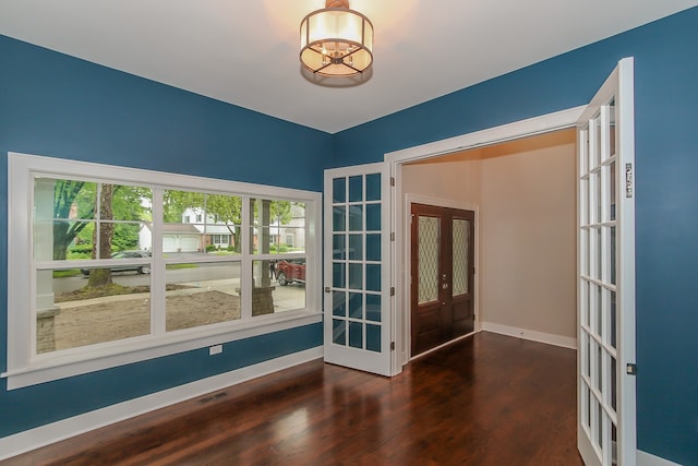 spare room featuring an inviting chandelier, french doors, and dark hardwood / wood-style flooring