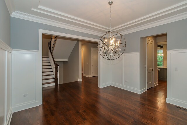 interior space featuring dark hardwood / wood-style flooring, ornamental molding, a tray ceiling, and a chandelier