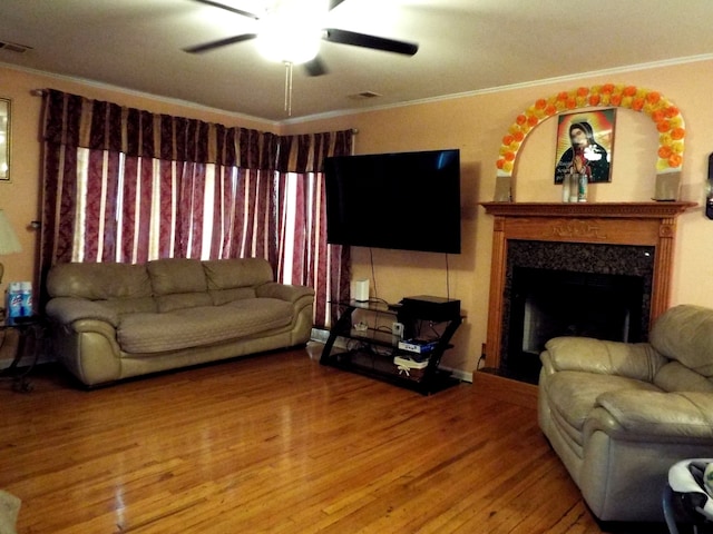 living room featuring ornamental molding, a fireplace, ceiling fan, and light wood-type flooring