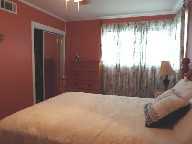 bedroom with multiple windows, crown molding, and a closet