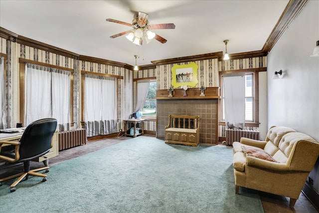 carpeted home office with radiator, a tiled fireplace, ornamental molding, and plenty of natural light