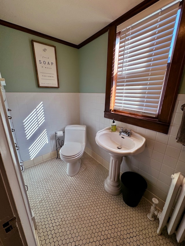 bathroom with radiator, toilet, and tile walls