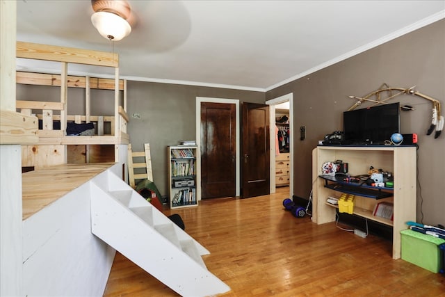 bedroom with ceiling fan, wood-type flooring, and ornamental molding