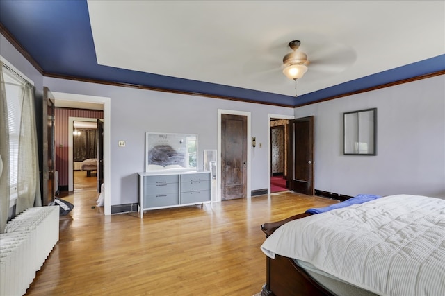 bedroom with radiator, ceiling fan, crown molding, and light wood-type flooring