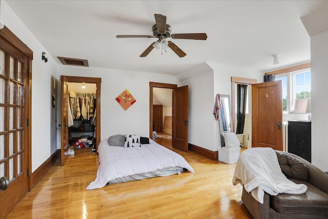 bedroom featuring a spacious closet, a closet, light wood-type flooring, and ceiling fan