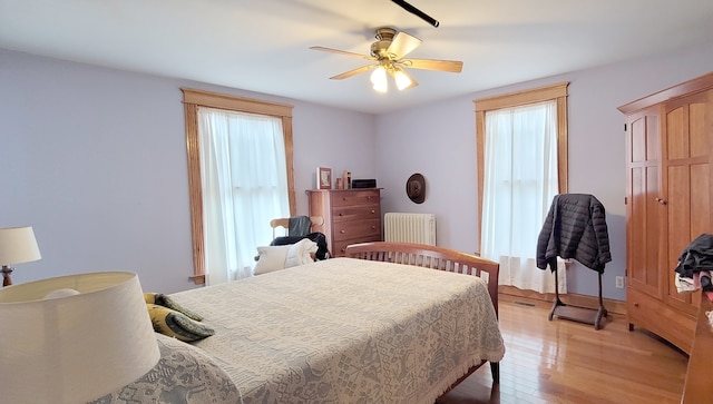 bedroom featuring light hardwood / wood-style floors, ceiling fan, and radiator