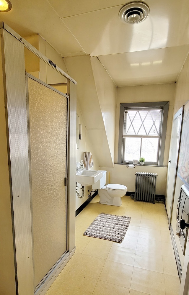 bathroom featuring toilet, sink, a shower with shower door, tile flooring, and radiator heating unit