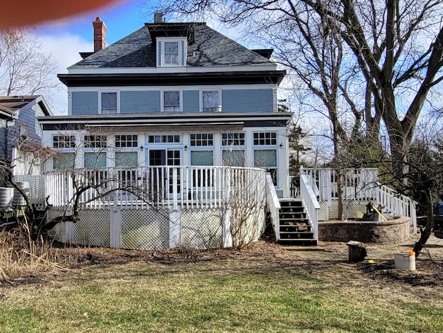 rear view of house featuring a lawn and a deck