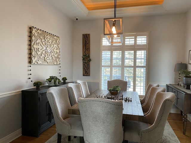 dining space featuring a raised ceiling and light wood-type flooring