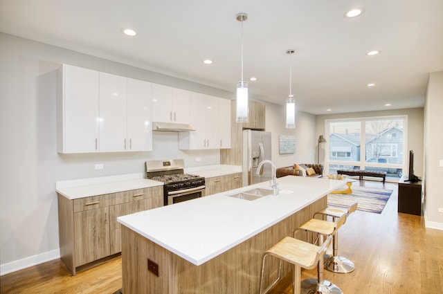 2520 S Stark St, Chicago, IL 60608 - kitchen featuring appliances with stainless steel finishes, light hardwood / wood-style floors, a kitchen breakfast bar, and white cabinets