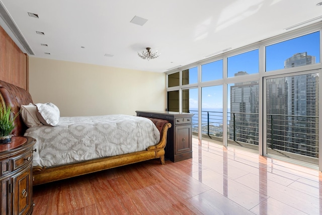 bedroom with a water view, a wall of windows, and light hardwood / wood-style floors