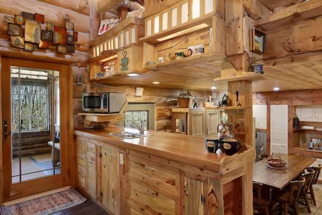 kitchen featuring wood counters, rustic walls, and sink