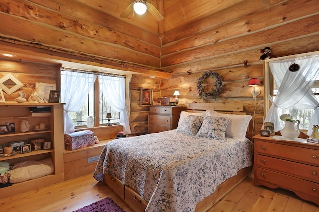 bedroom with log walls, ceiling fan, and light wood-type flooring