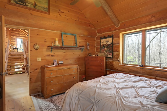 bedroom featuring ceiling fan, wood ceiling, light hardwood / wood-style floors, wood walls, and vaulted ceiling with beams