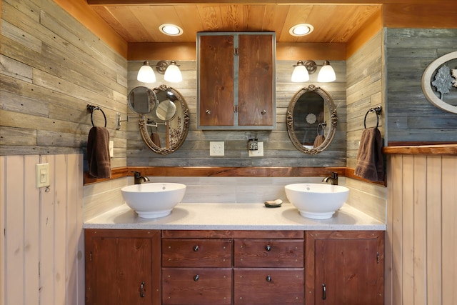 bathroom with dual vanity, backsplash, wood walls, and wood ceiling