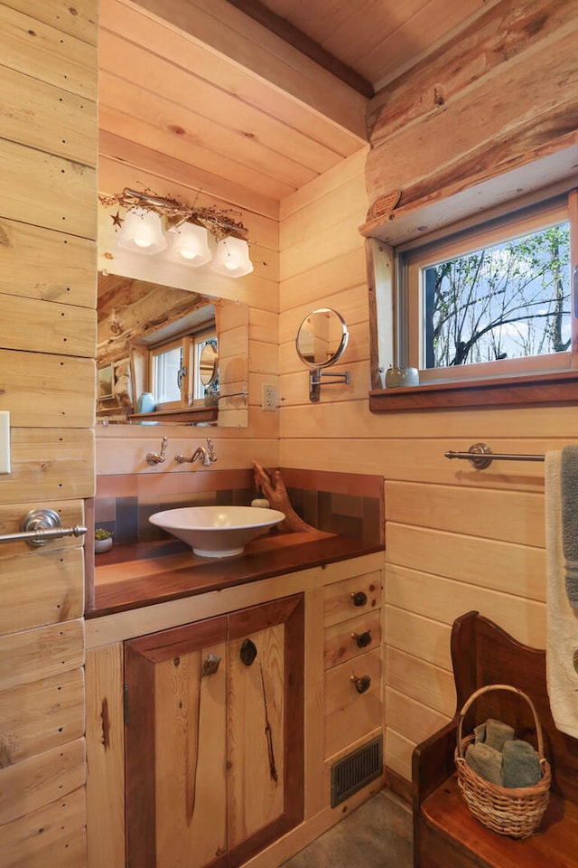 bathroom with vanity, wood walls, and wooden ceiling