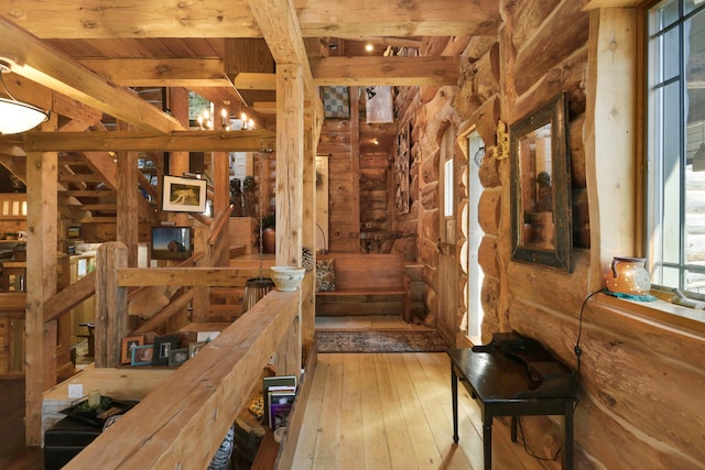 interior space with rustic walls, a notable chandelier, wood-type flooring, and beam ceiling