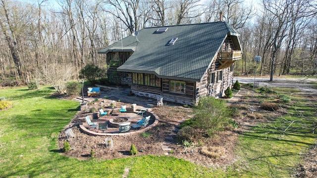 rear view of property with a fire pit, a yard, and a patio