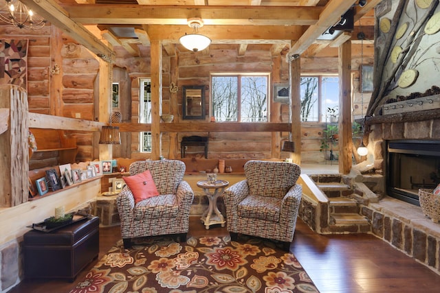 interior space featuring a chandelier, rustic walls, beamed ceiling, a stone fireplace, and dark hardwood / wood-style flooring