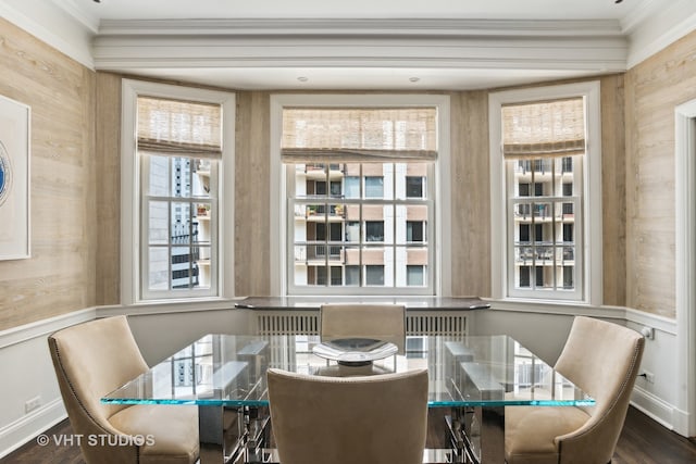 dining room with dark hardwood / wood-style flooring, ornamental molding, and wooden walls