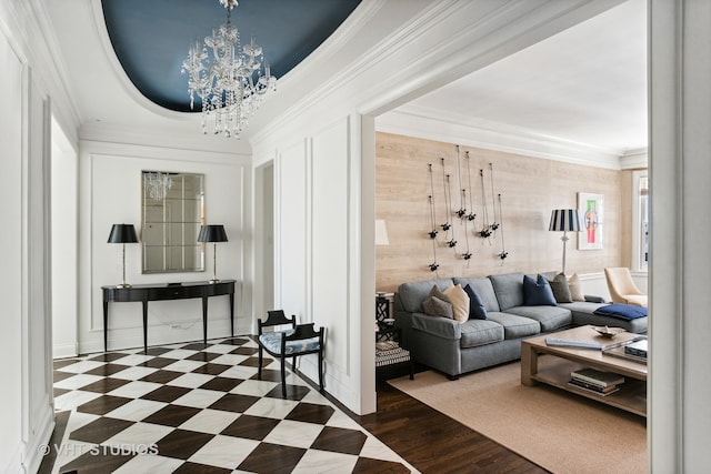 living room with dark tile flooring, ornamental molding, a chandelier, and a raised ceiling