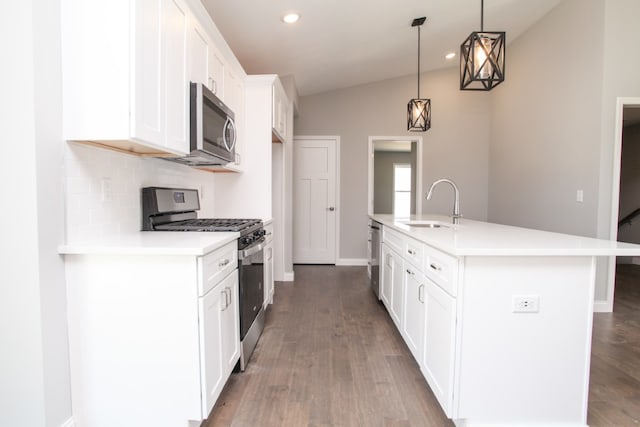 kitchen featuring an island with sink, appliances with stainless steel finishes, wood-type flooring, tasteful backsplash, and lofted ceiling