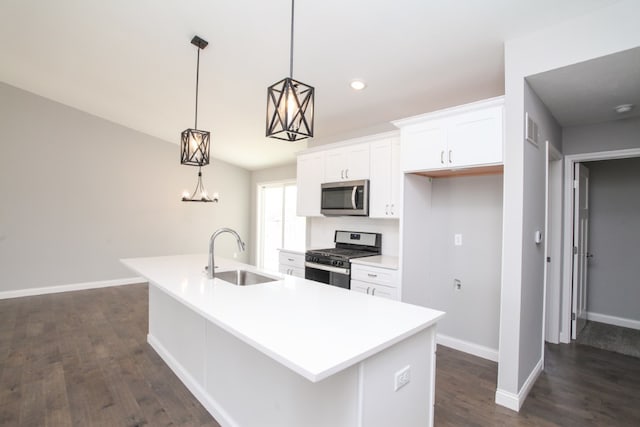 kitchen featuring decorative light fixtures, appliances with stainless steel finishes, dark hardwood / wood-style floors, a kitchen island with sink, and sink