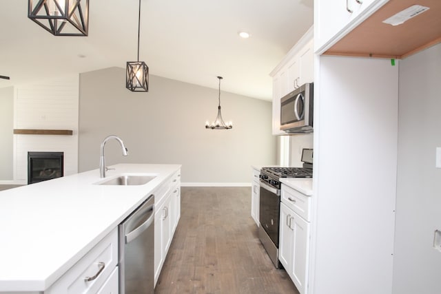 kitchen with appliances with stainless steel finishes, dark hardwood / wood-style floors, a kitchen island with sink, lofted ceiling, and sink