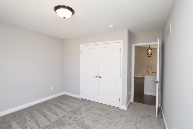 unfurnished bedroom with sink, light carpet, and a closet