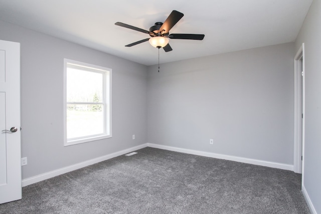 empty room with ceiling fan and dark colored carpet