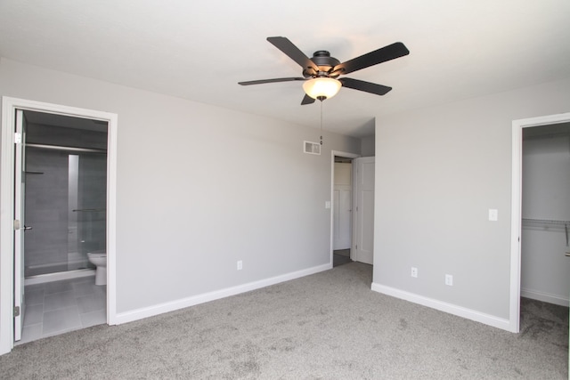 unfurnished bedroom featuring ceiling fan, a spacious closet, light carpet, ensuite bath, and a closet