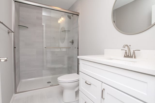 bathroom featuring a shower with shower door, tile floors, toilet, and oversized vanity