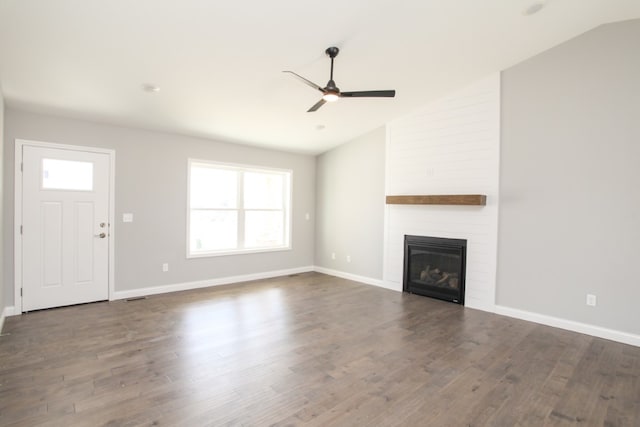 unfurnished living room with dark hardwood / wood-style flooring, a wealth of natural light, a large fireplace, and vaulted ceiling