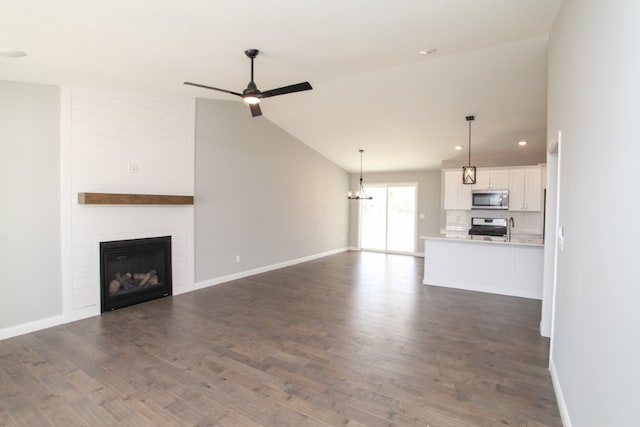 unfurnished living room featuring dark hardwood / wood-style flooring, a fireplace, ceiling fan with notable chandelier, and high vaulted ceiling