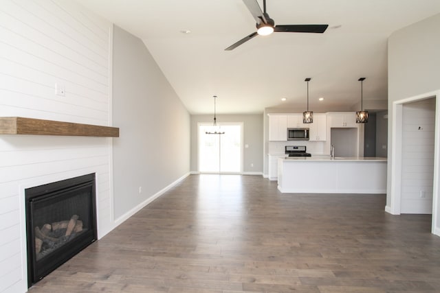 unfurnished living room with high vaulted ceiling, dark hardwood / wood-style floors, and ceiling fan with notable chandelier