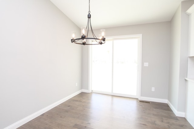 empty room with a notable chandelier and hardwood / wood-style floors