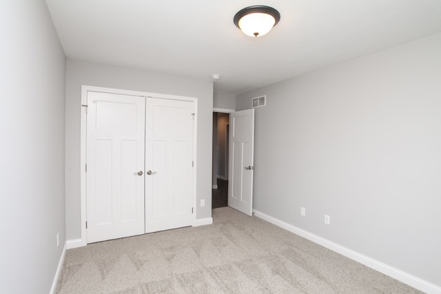 unfurnished bedroom with a closet and light colored carpet