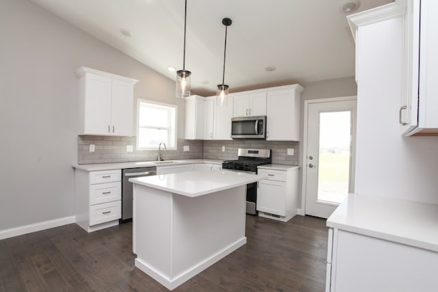 kitchen featuring appliances with stainless steel finishes, hanging light fixtures, a kitchen island, dark hardwood / wood-style flooring, and white cabinets