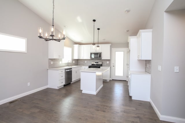 kitchen with hanging light fixtures, white cabinets, appliances with stainless steel finishes, and a center island